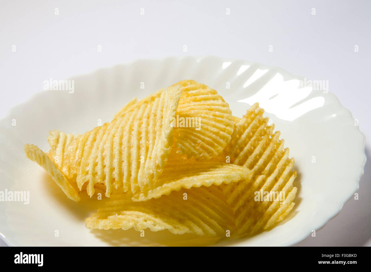 Junk food snacks salty potato chips or wafer served in plate Stock Photo