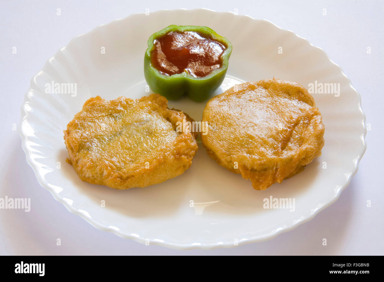 Indian fast food fried batata or potatoes vada with chopped green chilli served ih chutneys tomato ketchup served plate Stock Photo