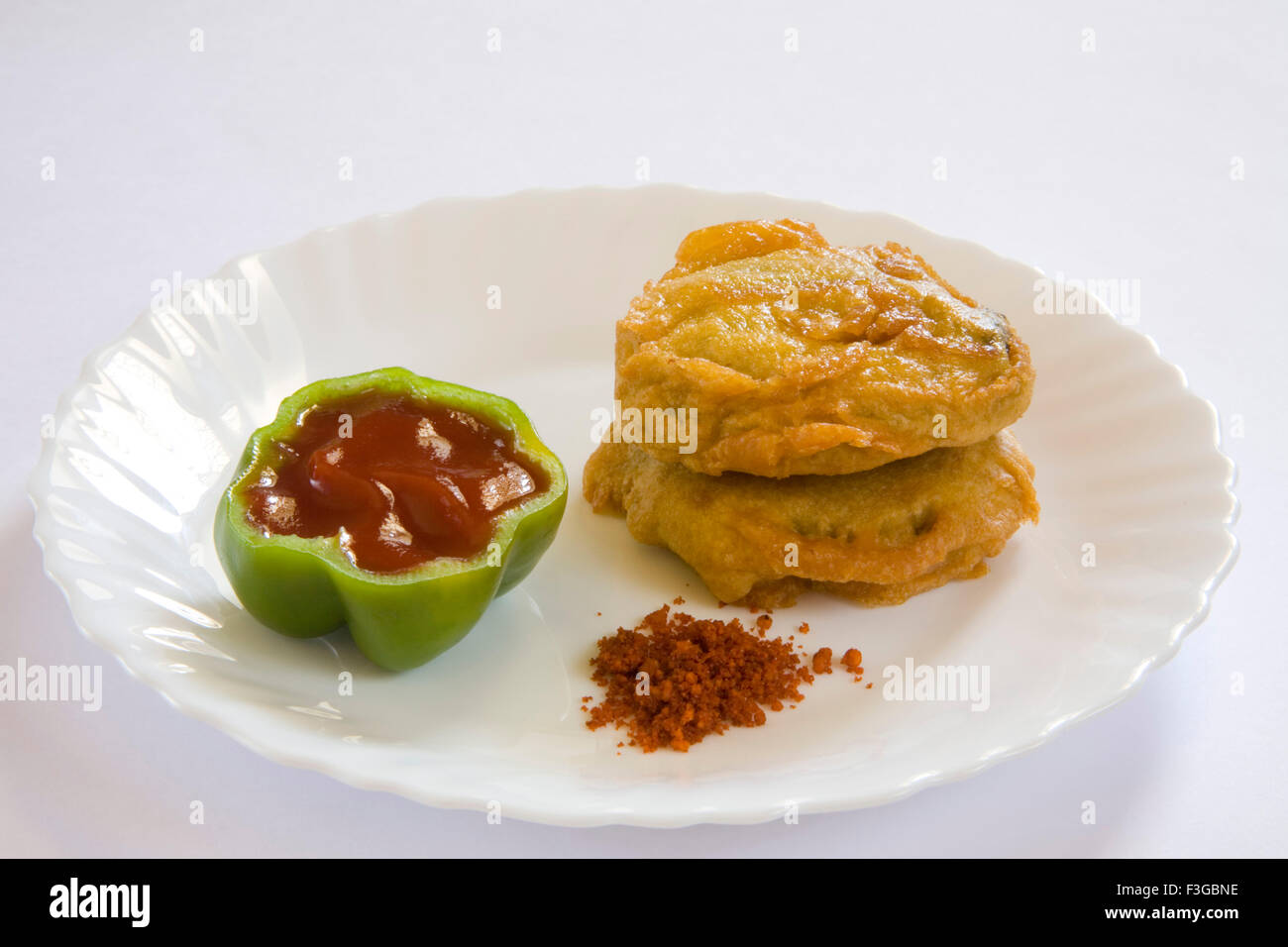 Indian fast food fried batata or potatoes vada with chopped green chilli served chutneys tomato ketchup served plate Stock Photo