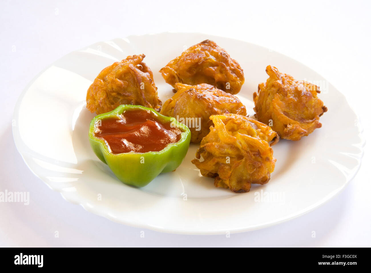 Indian fast food fried kanda bhaji served with tomato ketchup in plate ; India Stock Photo