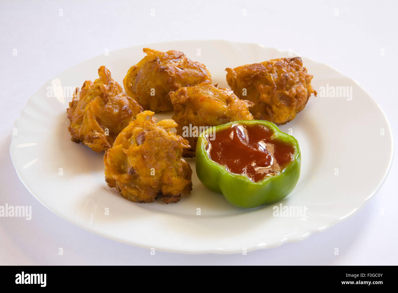 Indian fast food fried kanda bhaji served with tomato ketchup in plate ...