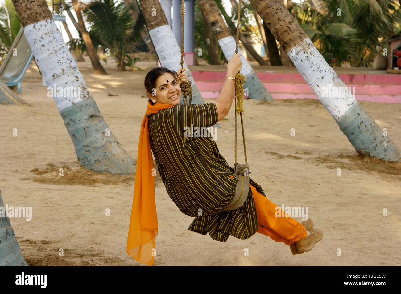 Woman on swing among coconut trees ; Murud Janjira ; Raigad ; Maharashtra ; India ; Asia Stock Photo
