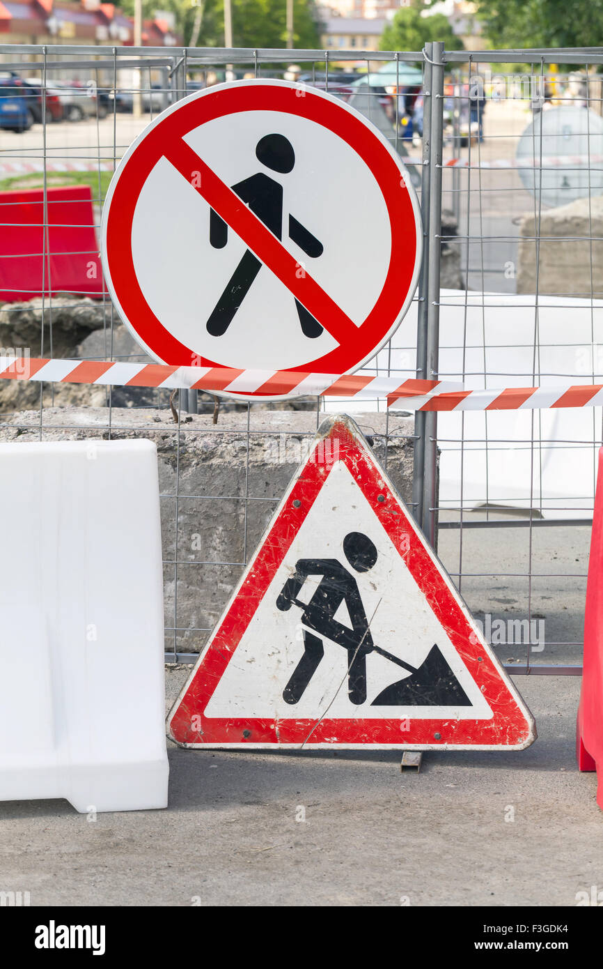 Roadworks border with street signs on the metal fence. Road under construction, no way Stock Photo