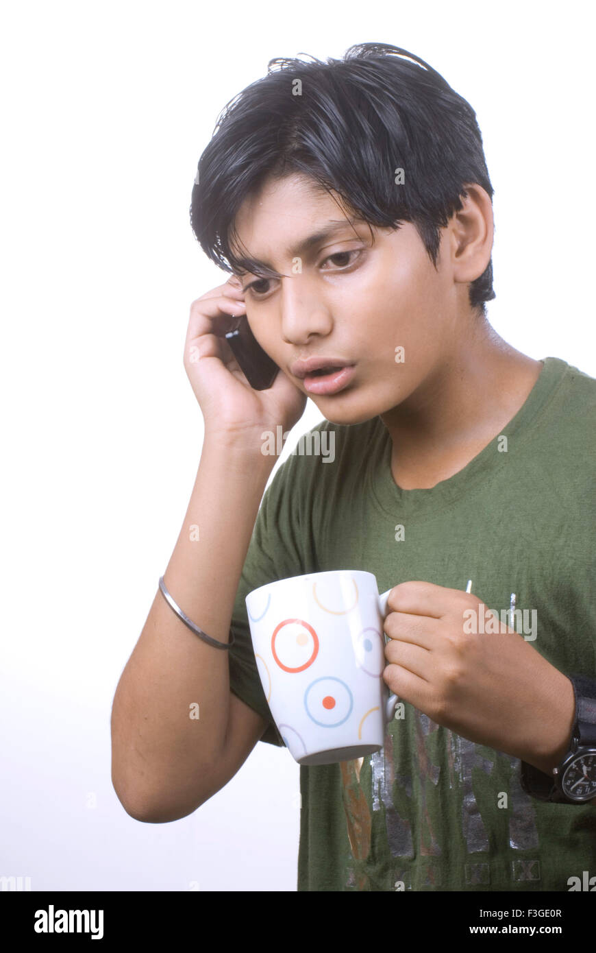 Teenager boy talking on mobile phone and holding mug of coffee MR#733 Stock Photo