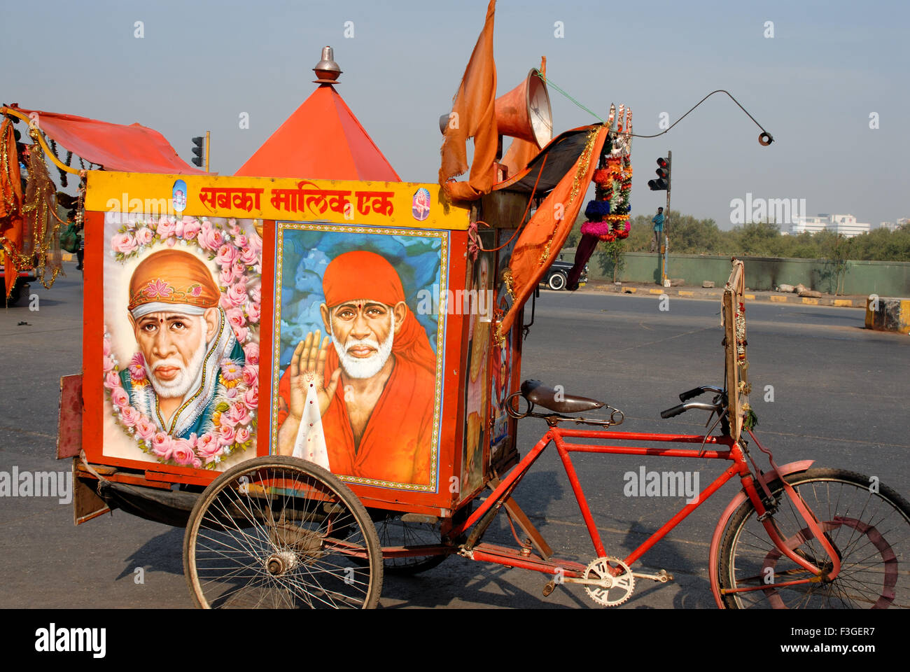 Publicity street to street Sai Baba God bicycle three wheeler bright orange color with loudspeaker Bombay Mumbai India Asia Stock Photo