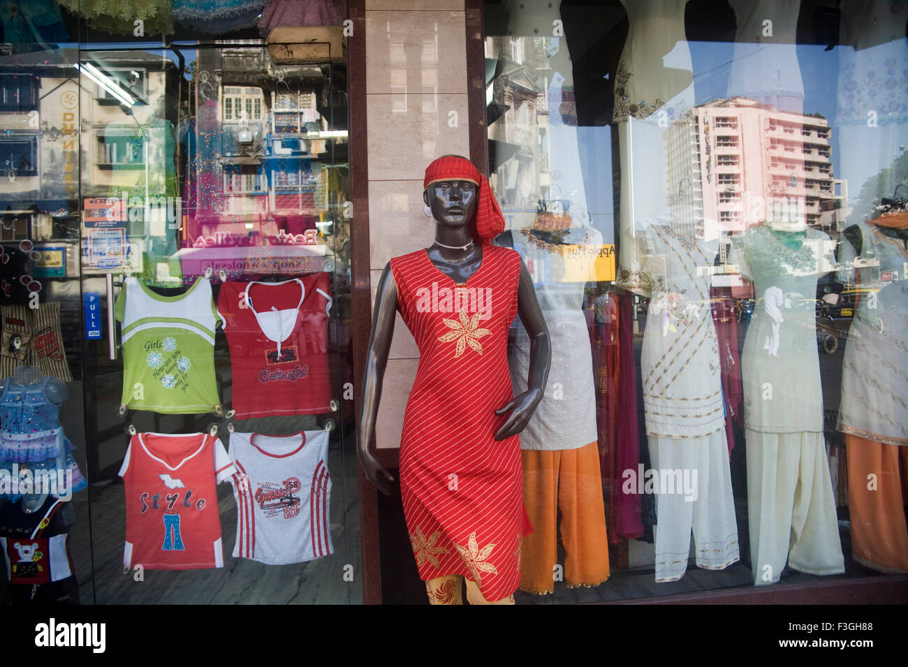 Mannequin in colorful garment in clothes shop and reflection on glass