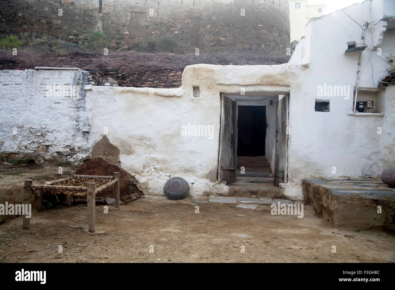 Old house with white wall opened door and cot old rural Indian architecture in Village Dilwara ; Udaipur ; Rajasthan Stock Photo