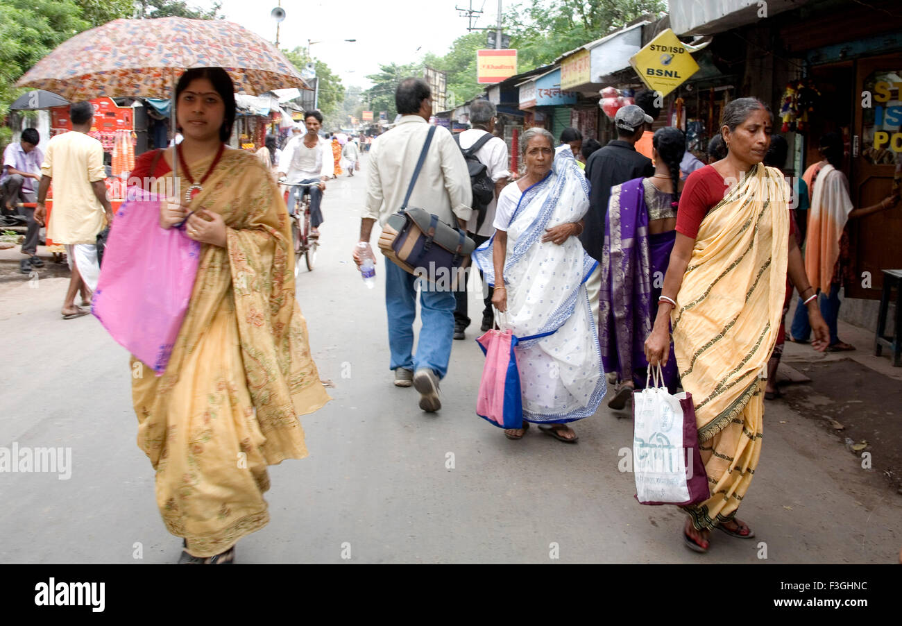 Indian women in traditional Bengali sari holding umbrella Dakshineshwar market street Calcutta Kolkata West Bengal India Stock Photo
