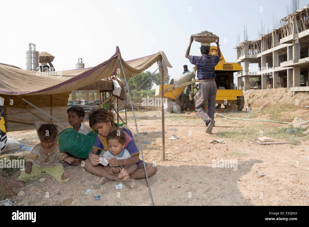 Children of construction workers play under a temporary shelter while their parents Ahmedabad Stock Photo