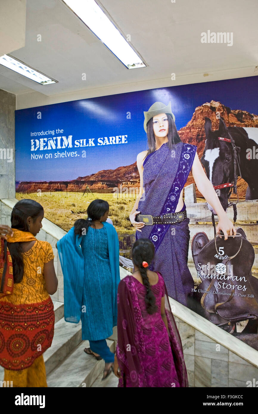 Indian women looking at poster showing model with cowboy hat gun holster holding saddle with horse at sari shop, Madras, Chennai, Tamil Nadu, India, Asia Stock Photo