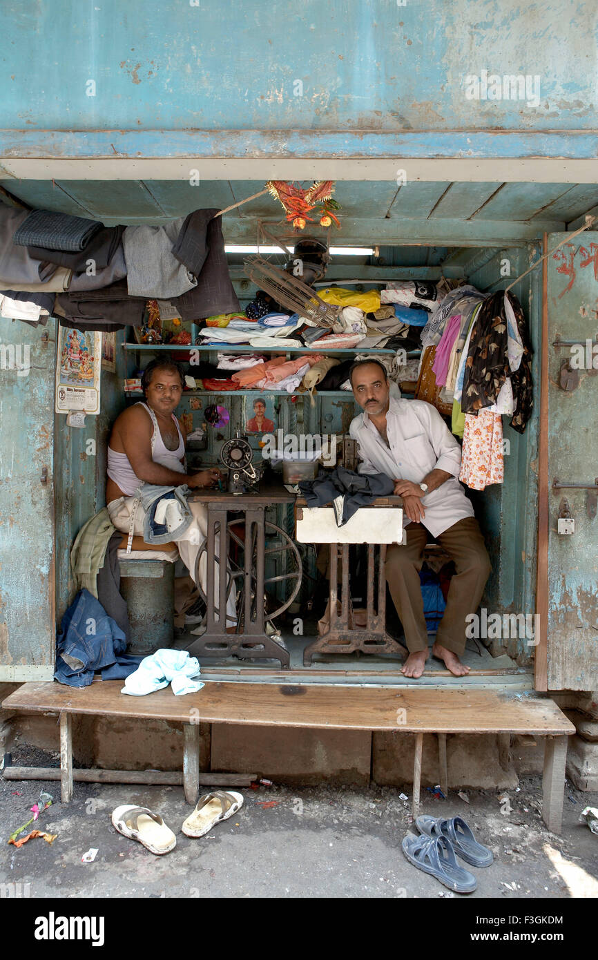 A space literally fit enough to put two sewing machines and stools becomes a busy tailor's shop ; Mumbai Bombay ; Maharashtra Stock Photo
