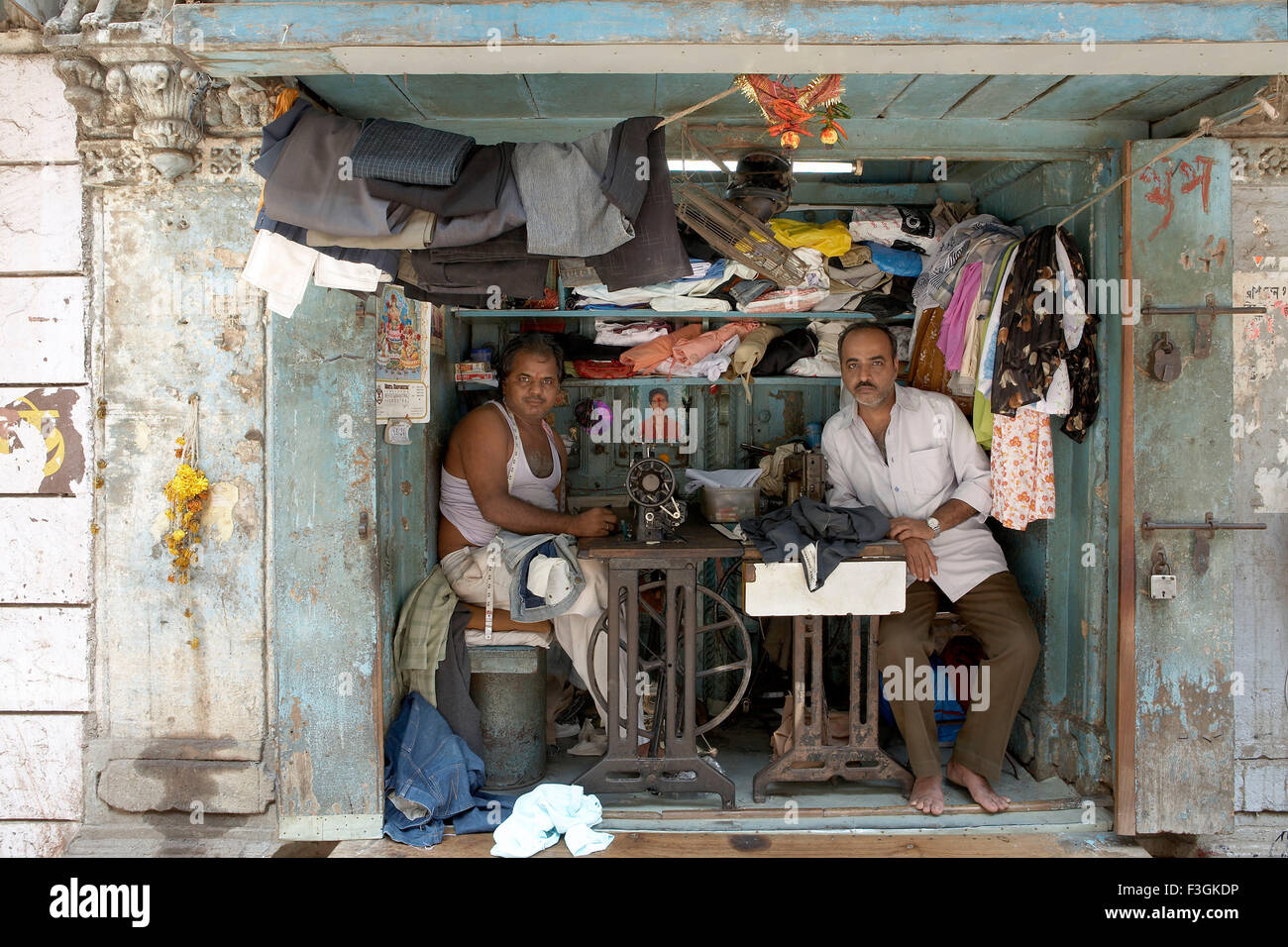 A space literally fit enough to put two sewing machines and stools becomes a busy tailor's shop ; Mumbai Bombay ; Maharashtra Stock Photo