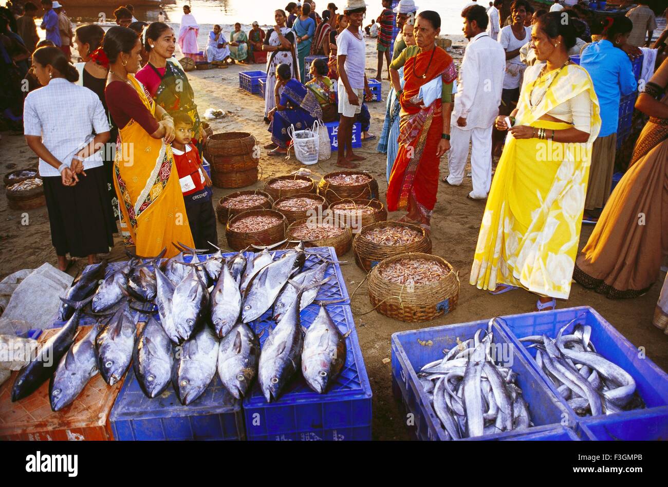 People buying and selling fish in beach bazaar ; India Stock Photo