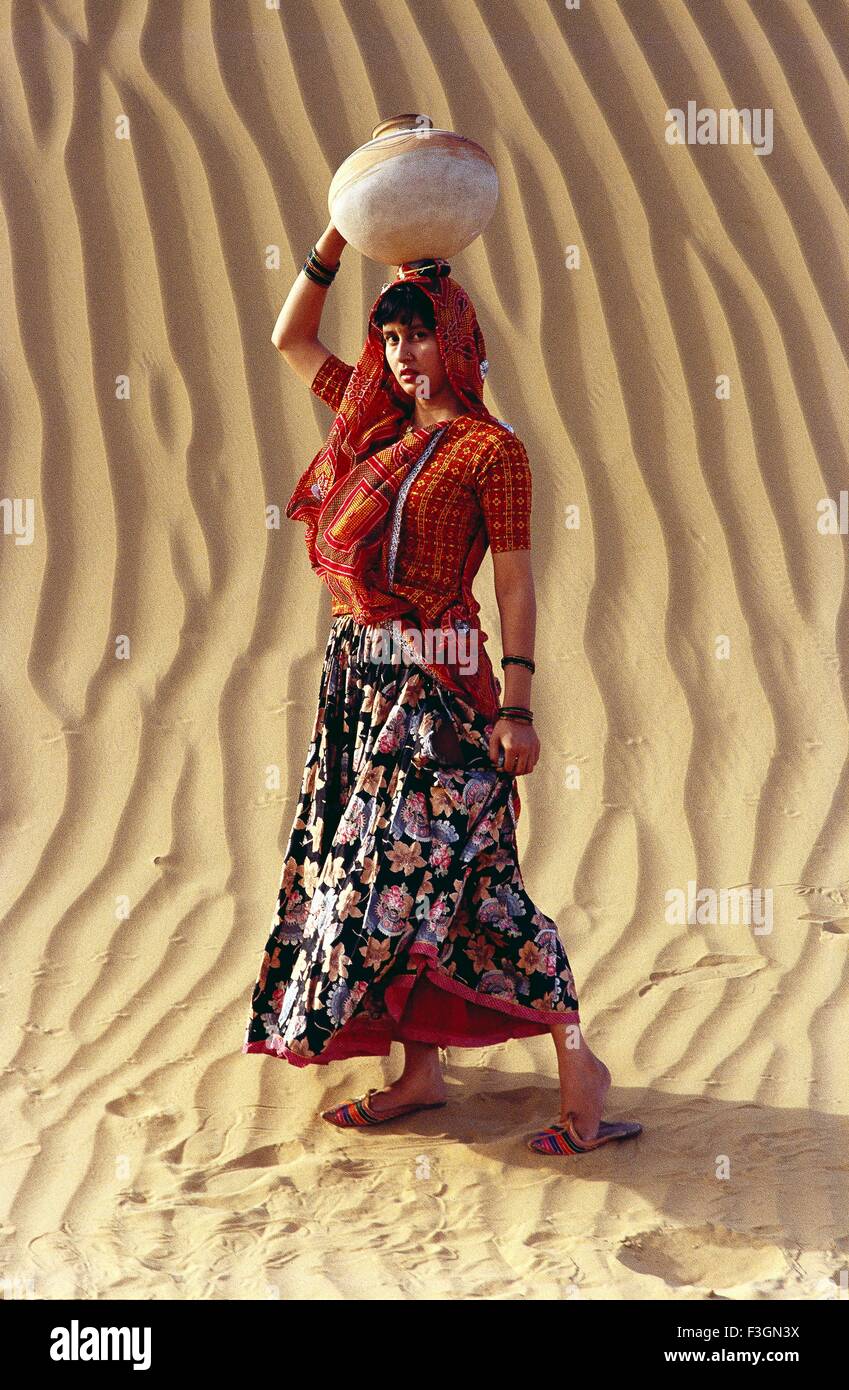 Rajasthani woman holding clay pot on head desert sand in background Bikaner Rajasthan India Model Released Stock Photo