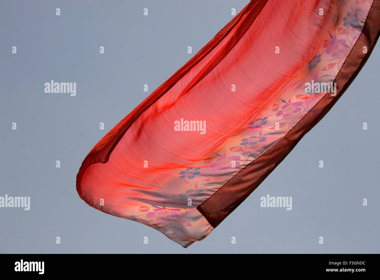 Abstract Indian traditional ladies wear saree red color flying air against blue skies wind while hanging drying wash Pune Stock Photo