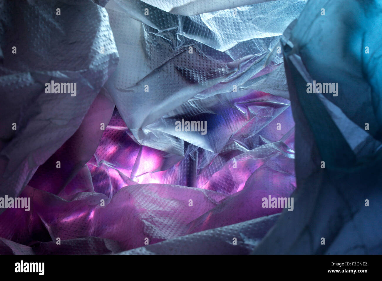 Abstract of plastic shopping bag on pink gift wrapping paper in blue and red light ; Pune ; Maharashtra ; India Stock Photo