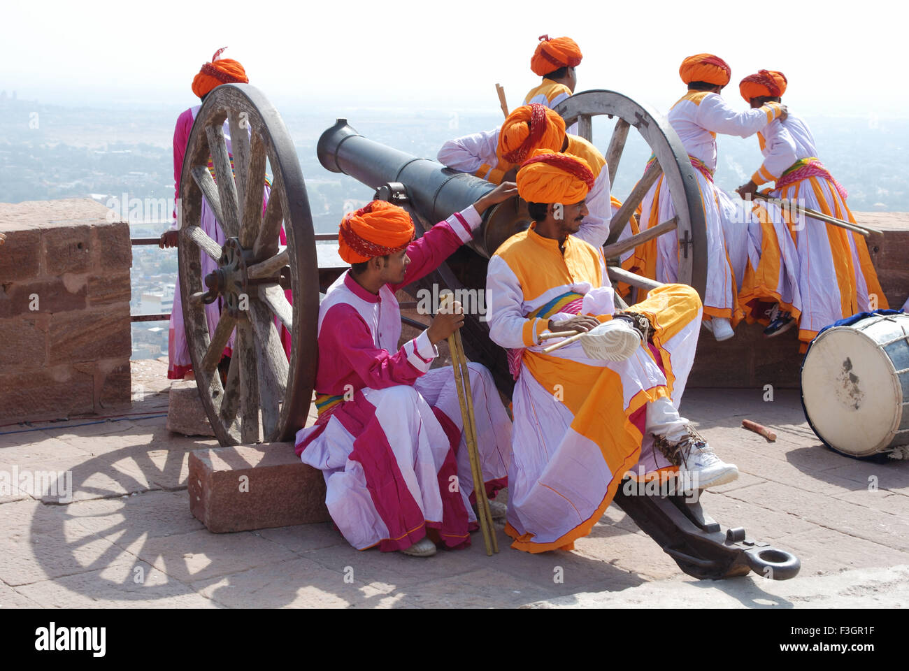 Gair dancers in relax mood sitting on cannon ; Jodhpur ; Rajasthan ; India Stock Photo