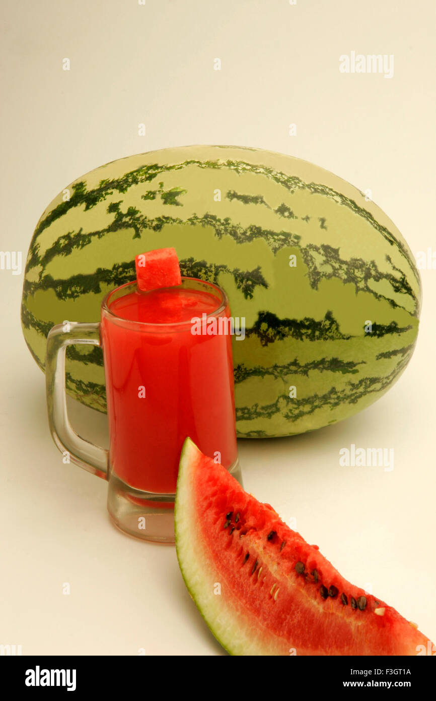 Fruits watermelon light dark green stripes one cut slice showing red watery pulp black seeds glass melon juice Pune Maharashtra Stock Photo