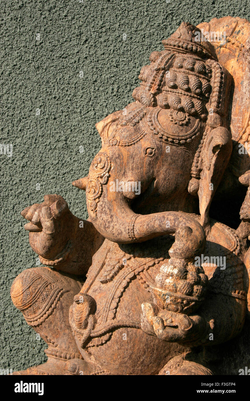 Indian heritage art in the form of stone sculpture of lord Ganesh elephant headed god against textured wall ; Pune Stock Photo