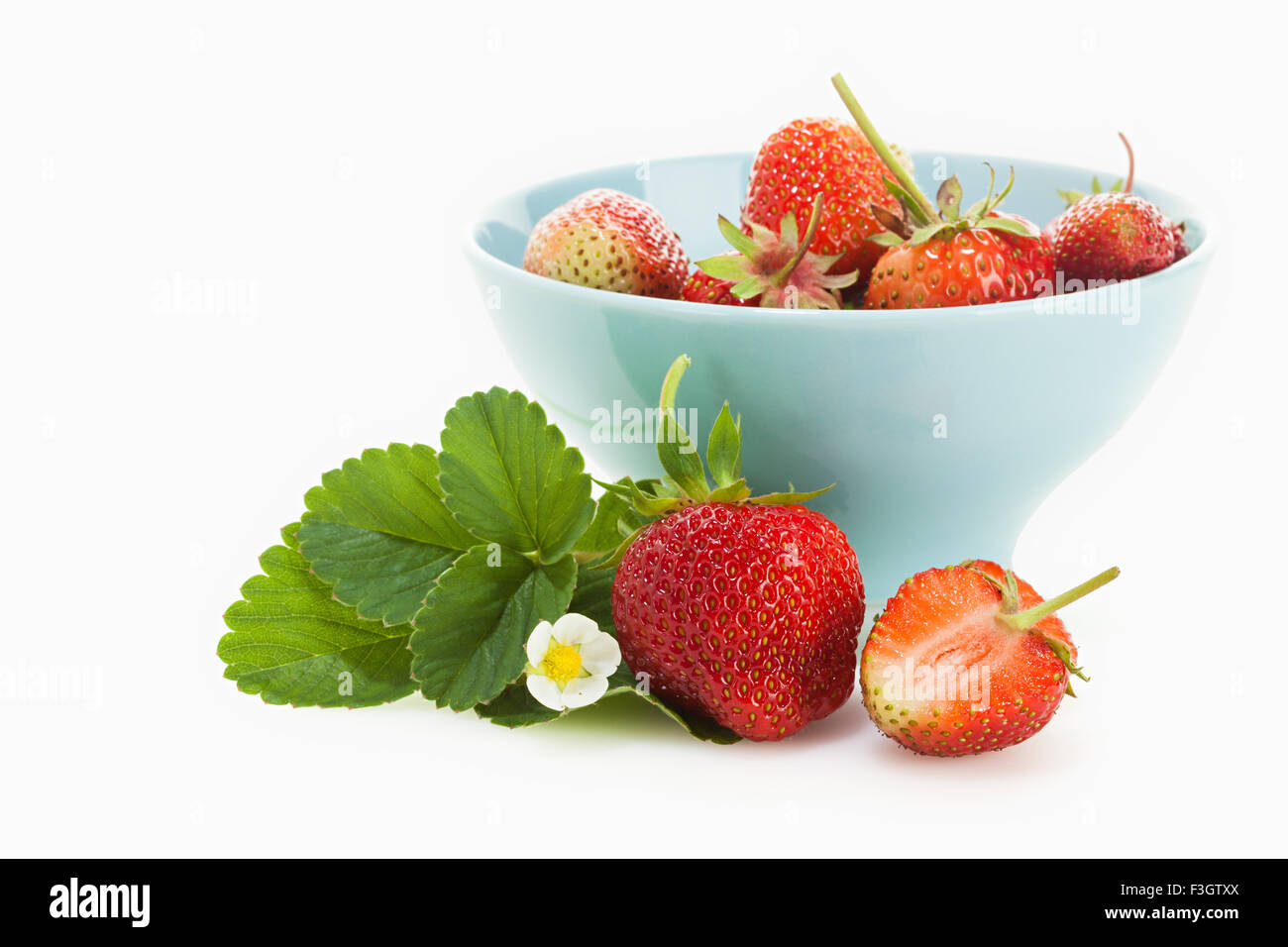 Mieze Schindler variety strawberries with their leaves and blossom in and around bowl isolated on white background Stock Photo