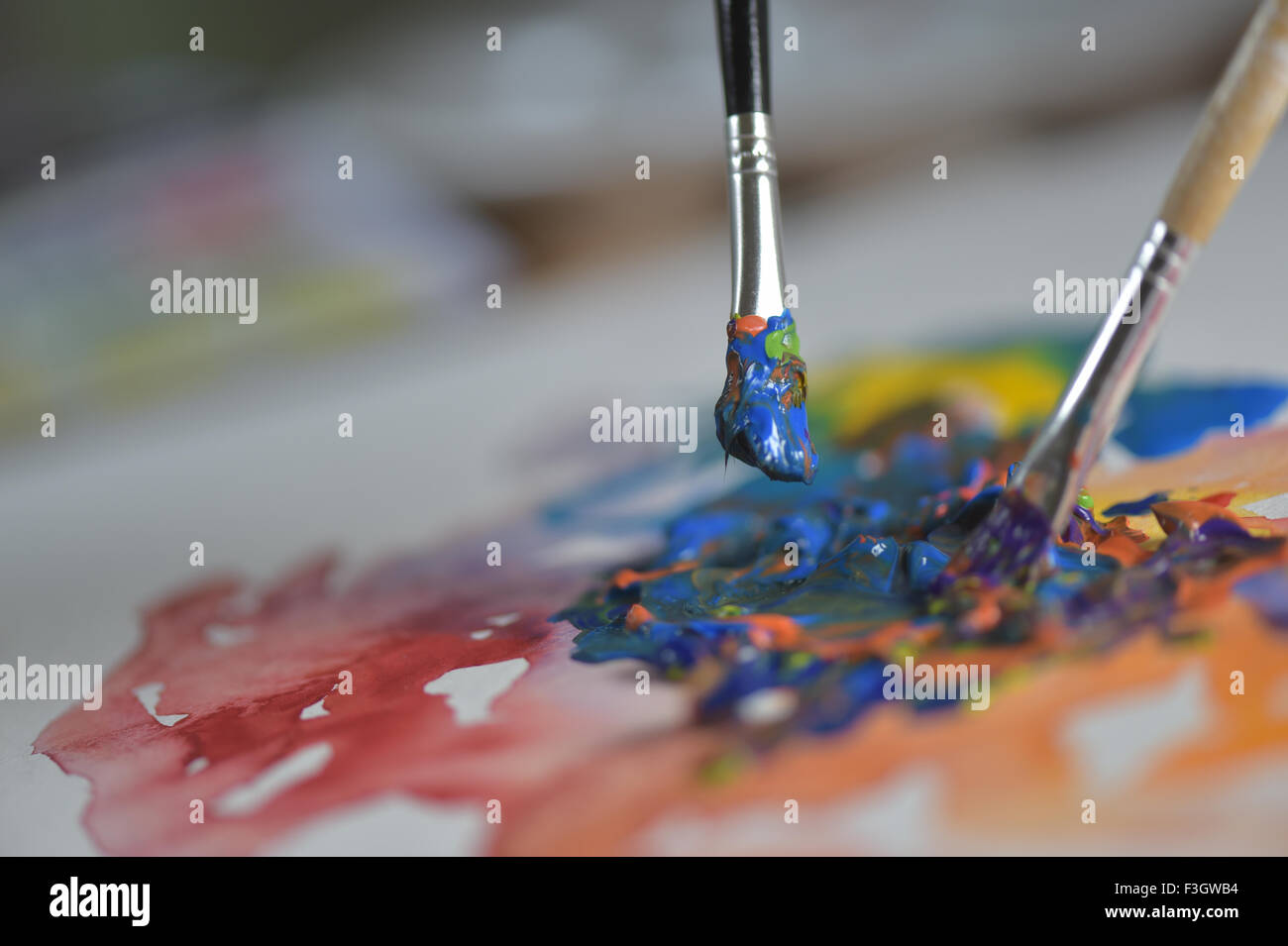 Brush mixing paint on paletteArtist's hand applying paint gouache on