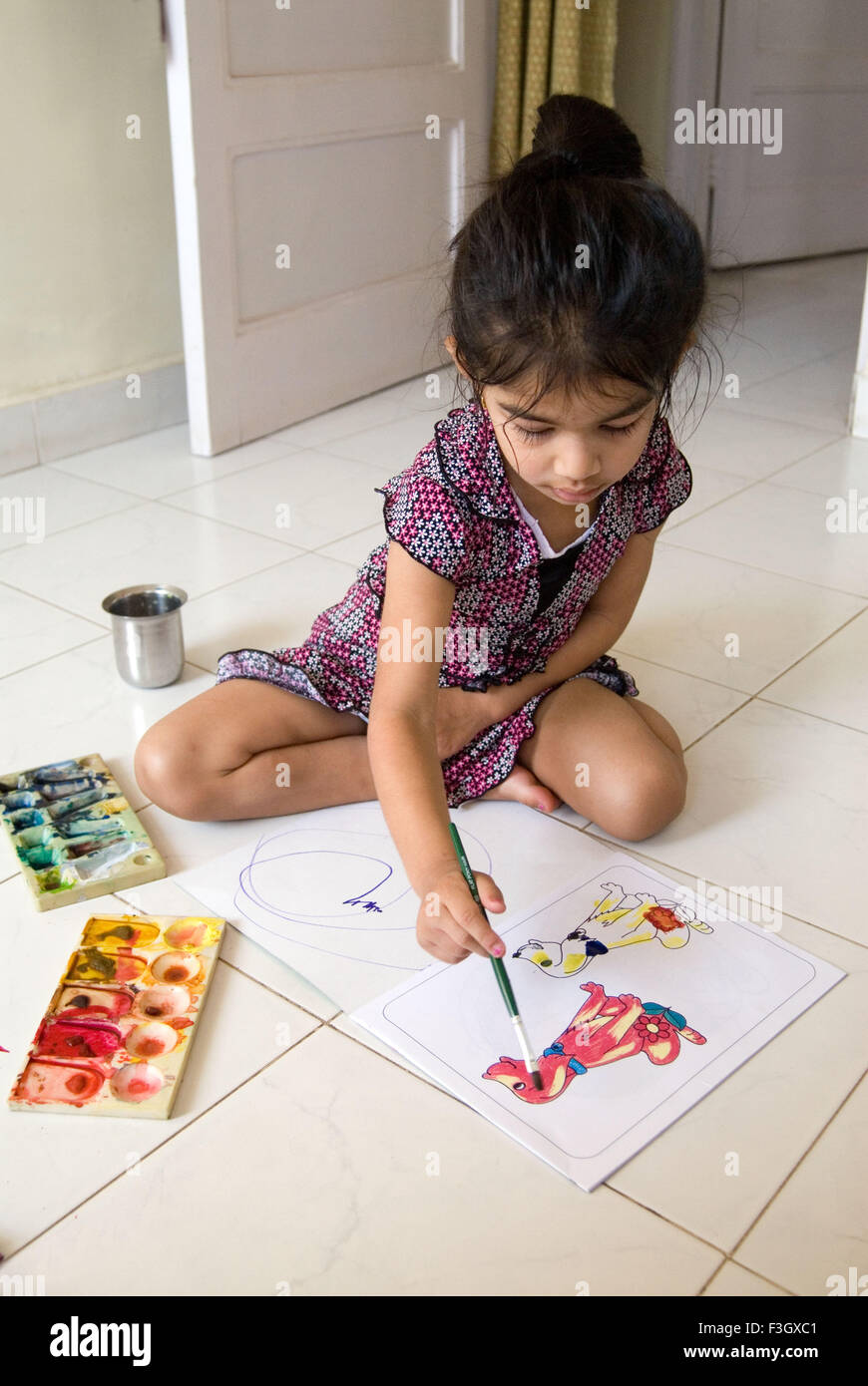 Four years old girl filling watercolour with brush in sketch MR#556 Stock Photo