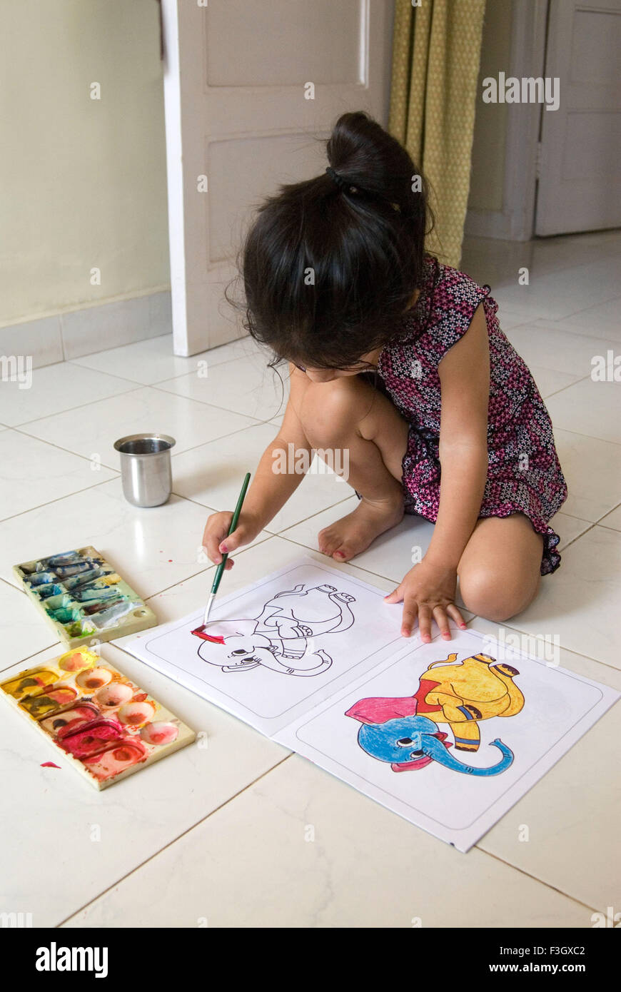 Four years old girl filling watercolour with brush in sketch MR#556 Stock Photo