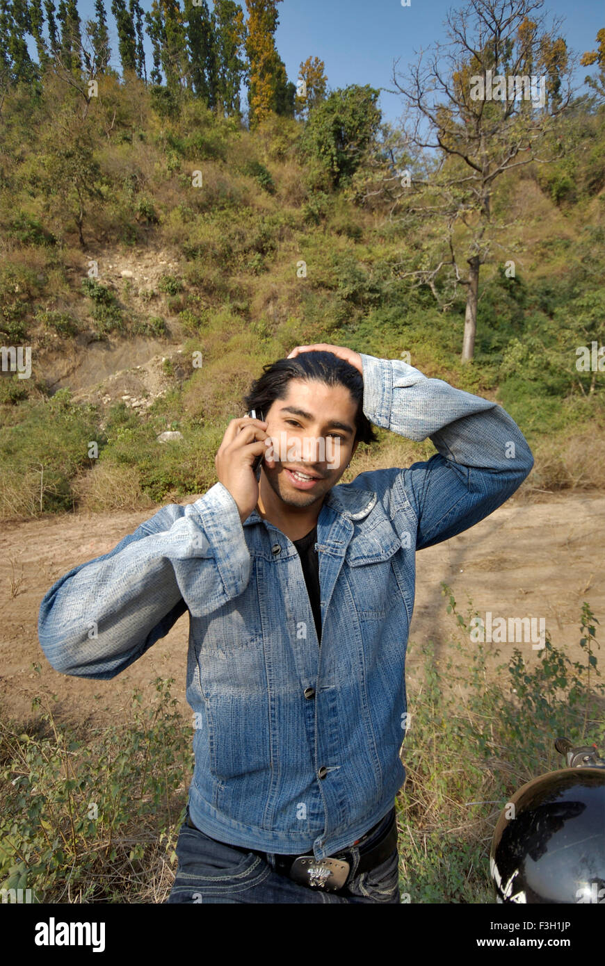 A young male talking on mobile phone ; Dehradun ; Uttaranchal ; India Stock Photo