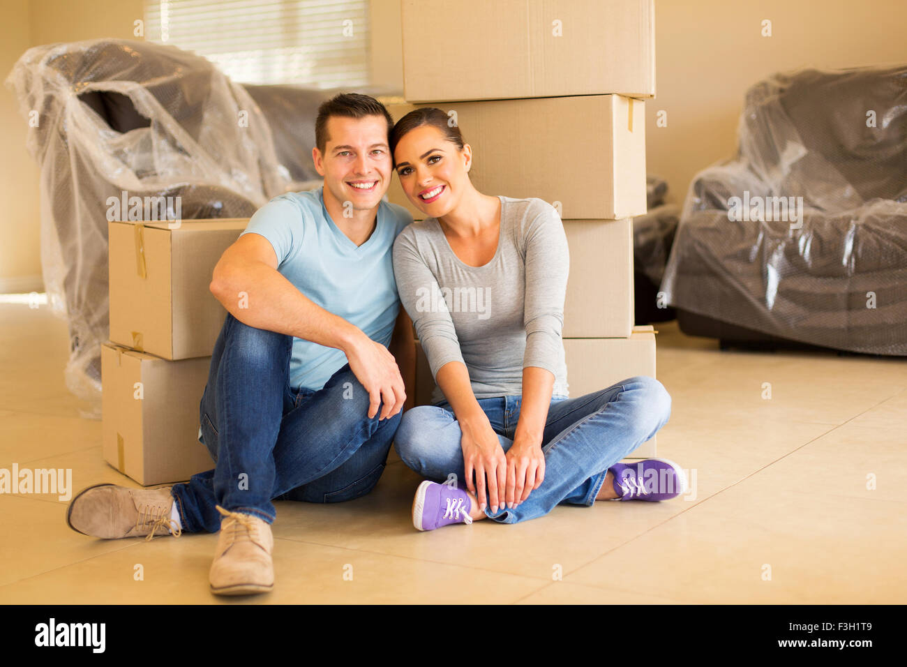 portrait of happy couple sitting in new house Stock Photo - Alamy