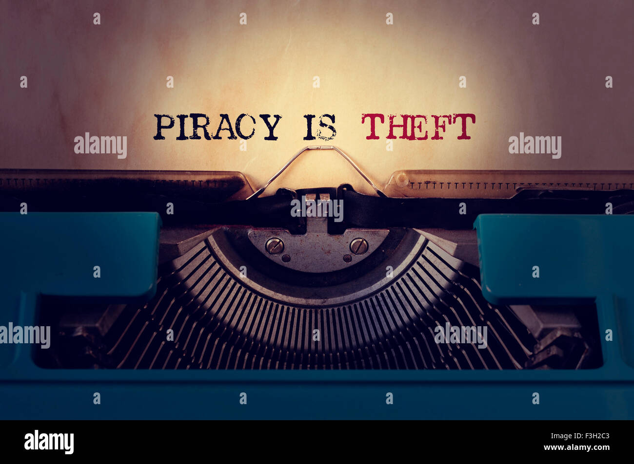 closeup of a blue retro typewriter and the text piracy is theft written with it in a yellowish foil Stock Photo