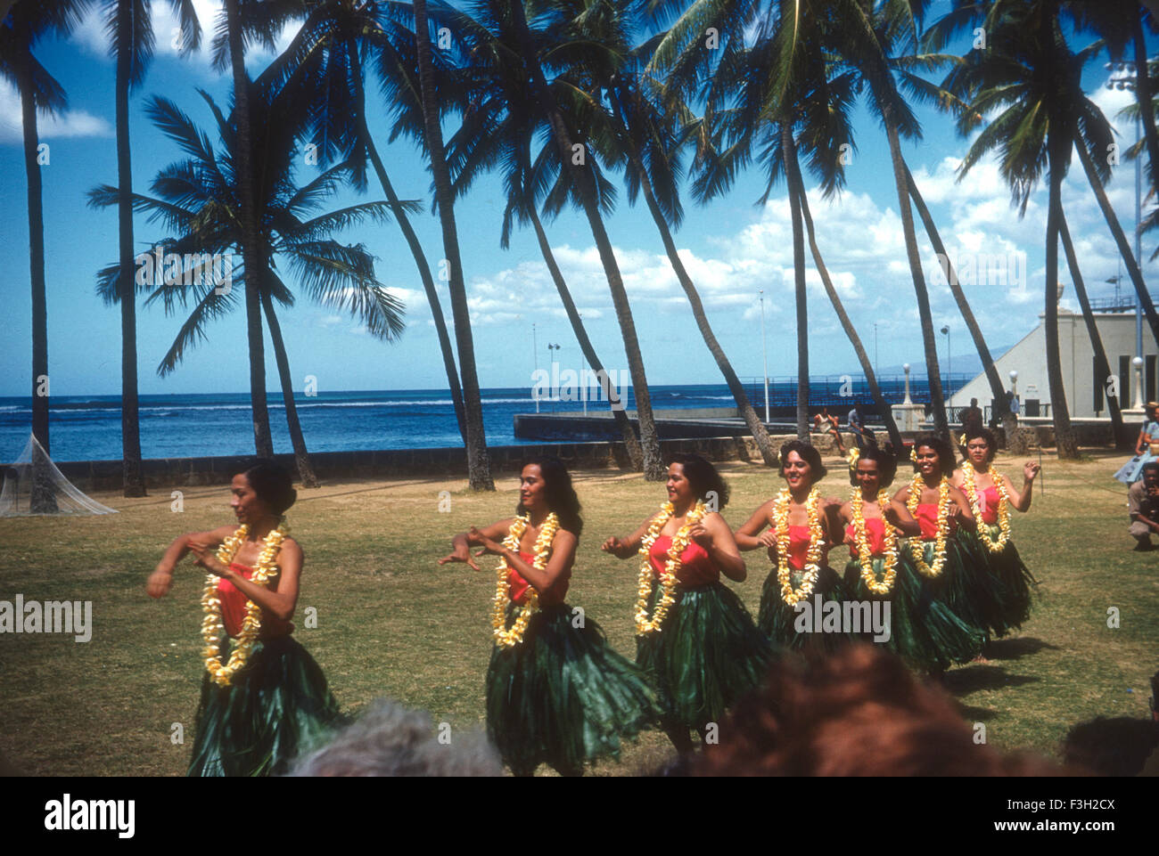 Tourists attend a luau in Hawaii during the 1950s with entertainment by Hawaiians. hula dancers dancing an wearing leis Stock Photo