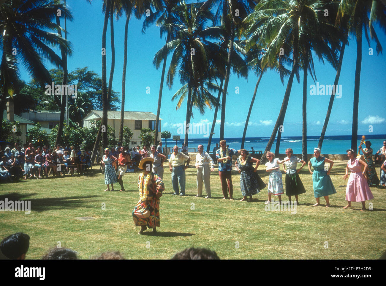 Tourists attend a luau in Hawaii during the 1950s with entertainment by