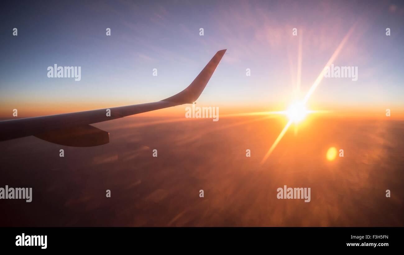 Wing of plane seen from aeroplane window, at sunset Stock Photo