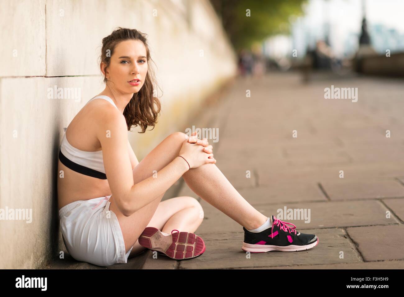 Portrait of young female runner sitting on riverside Stock Photo