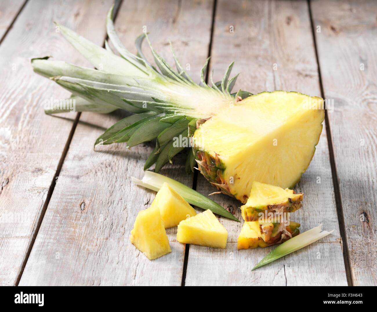 Quarter pineapple and leaves on whitewashed wooden table Stock Photo