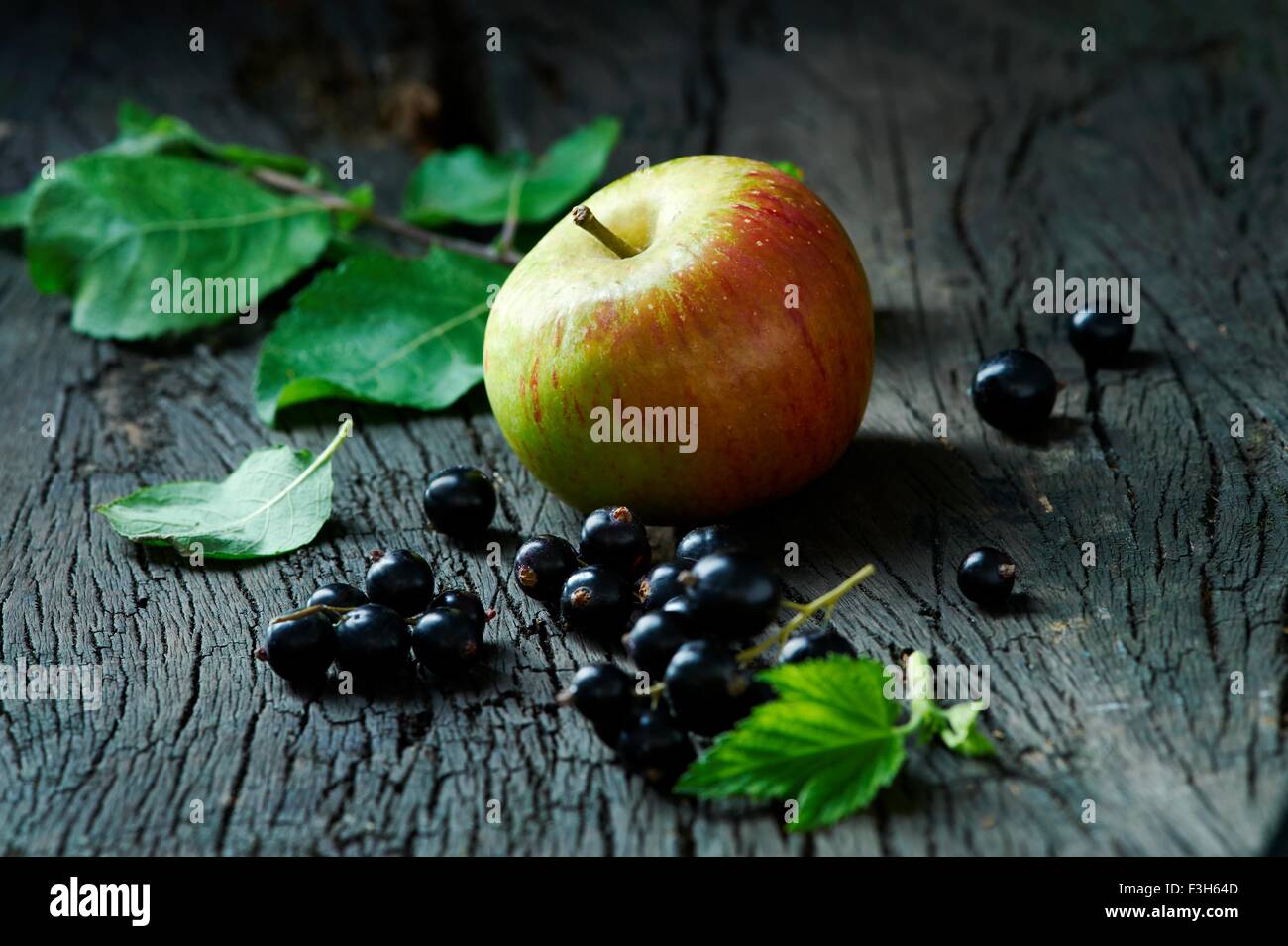 Cox's apples and blackcurrants on old wooden surface Stock Photo