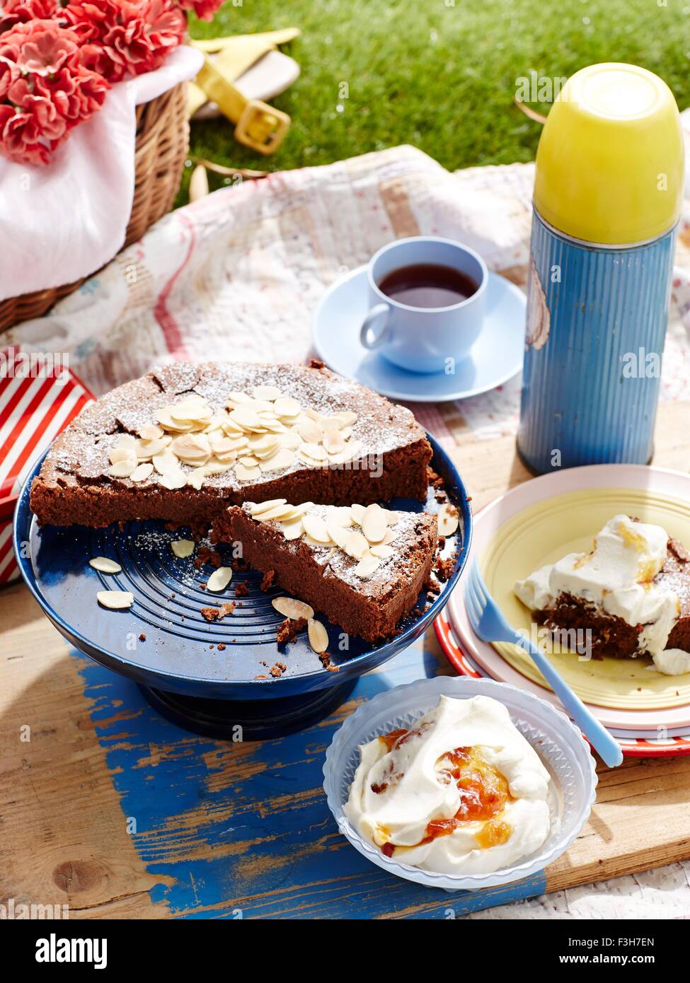 Chocolate cake and drinks flask on picnic blanket, close-up Stock Photo