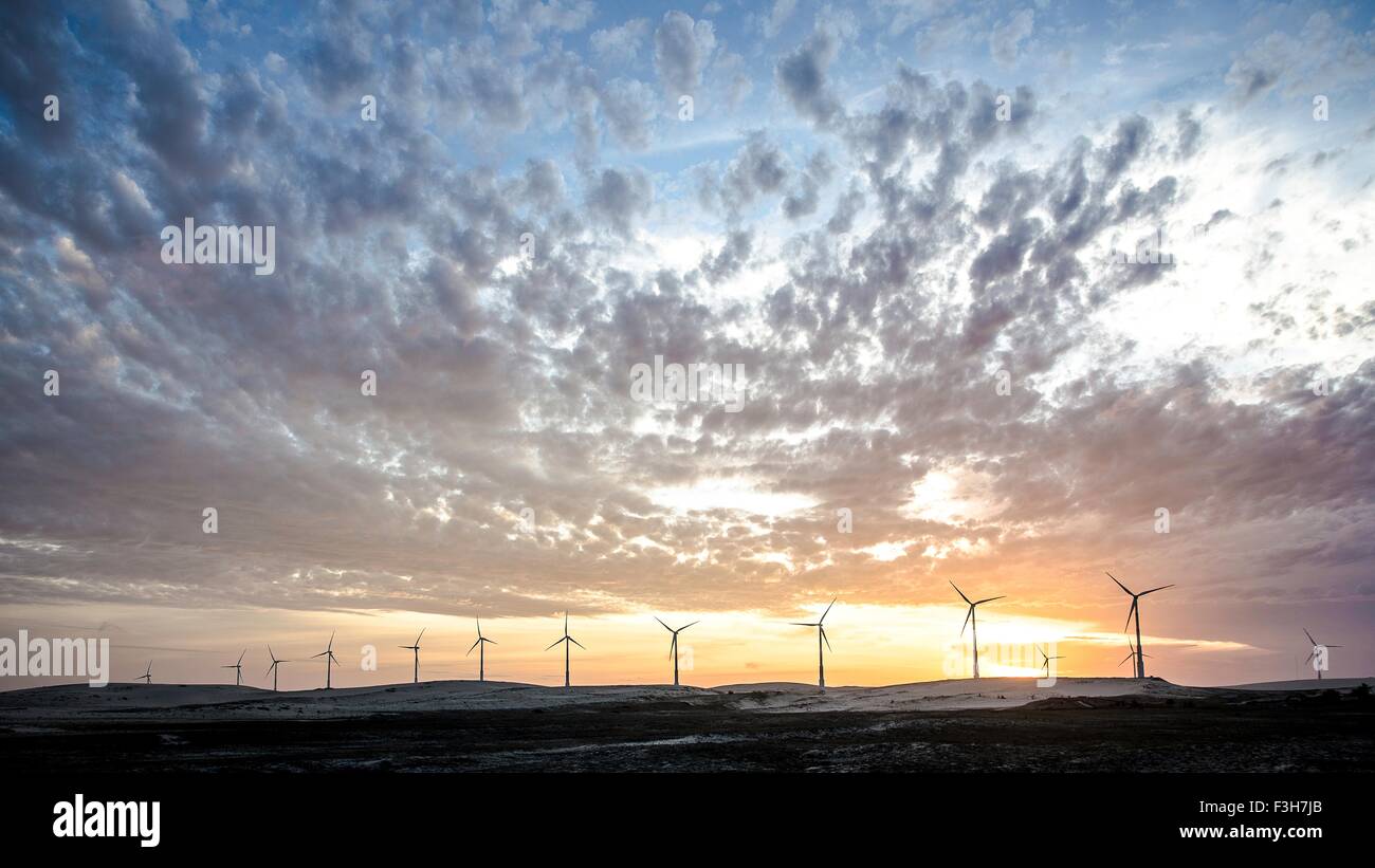 Wind turbines in a row on wind farm against dramatic sky Stock Photo