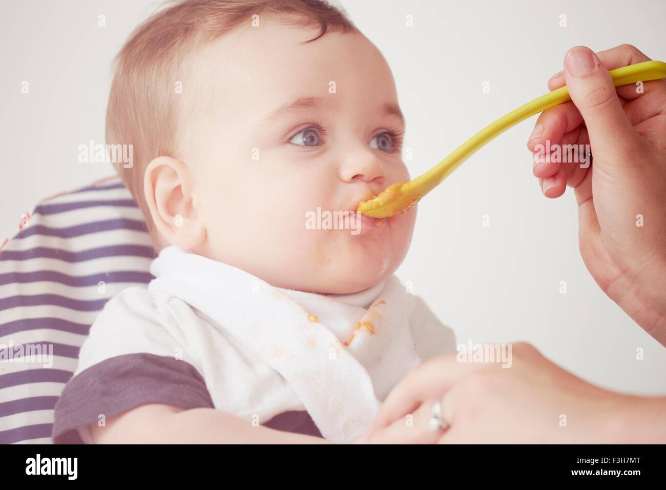 Mother feeding baby boy in baby chair Stock Photo