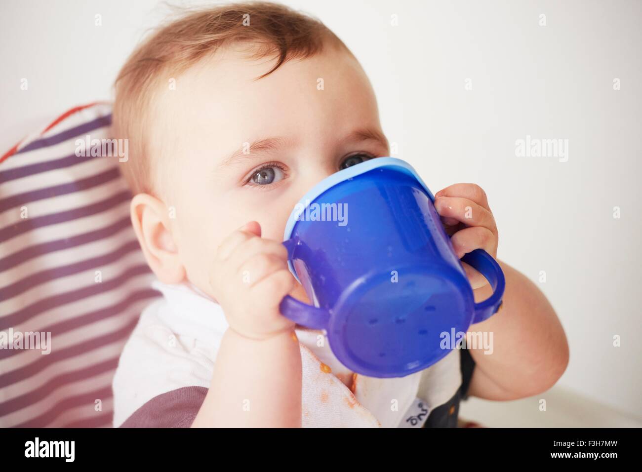 Baby boy drinking in baby chair Stock Photo