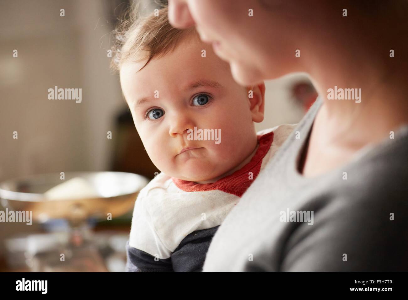 Mother carrying baby boy in kitchen Stock Photo