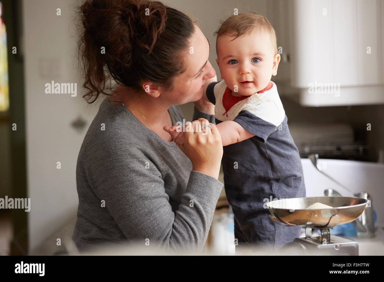 Mother holding baby boy on kitchen counter Stock Photo