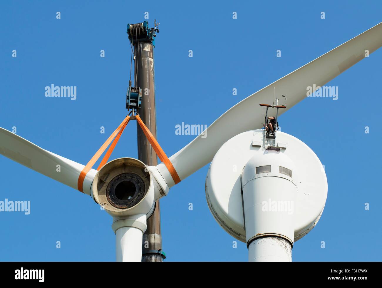 Low angle view of wind turbine being dismantled by worker Stock Photo