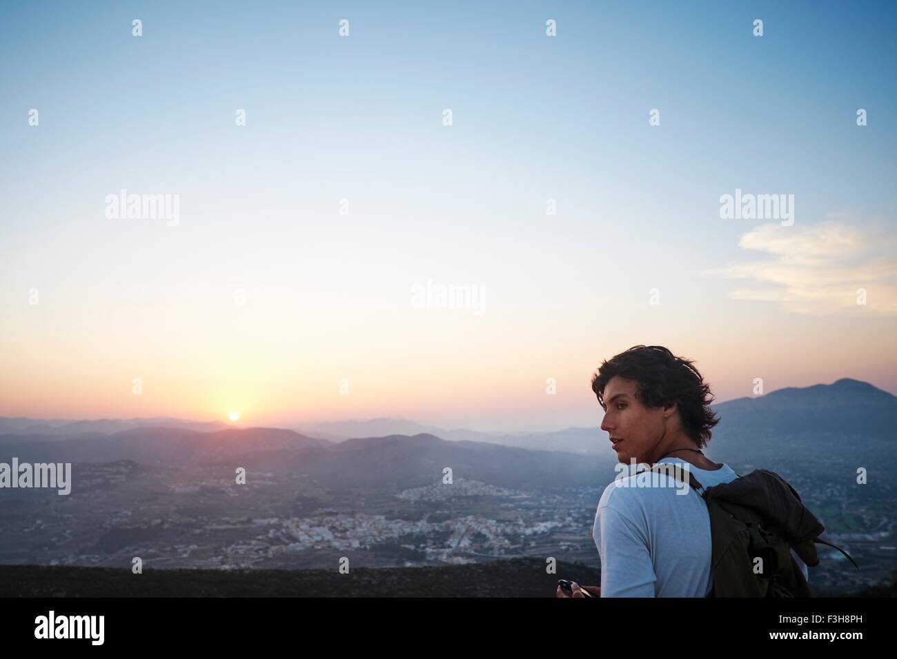 Young man looking out at landscape and sunset, Javea, Spain Stock Photo