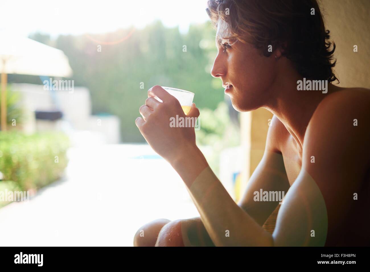 Young man drinking soft drink on patio chair Stock Photo