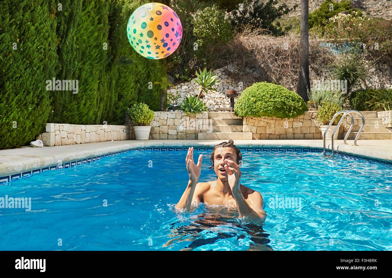 Young man throwing ball in swimming pool Stock Photo