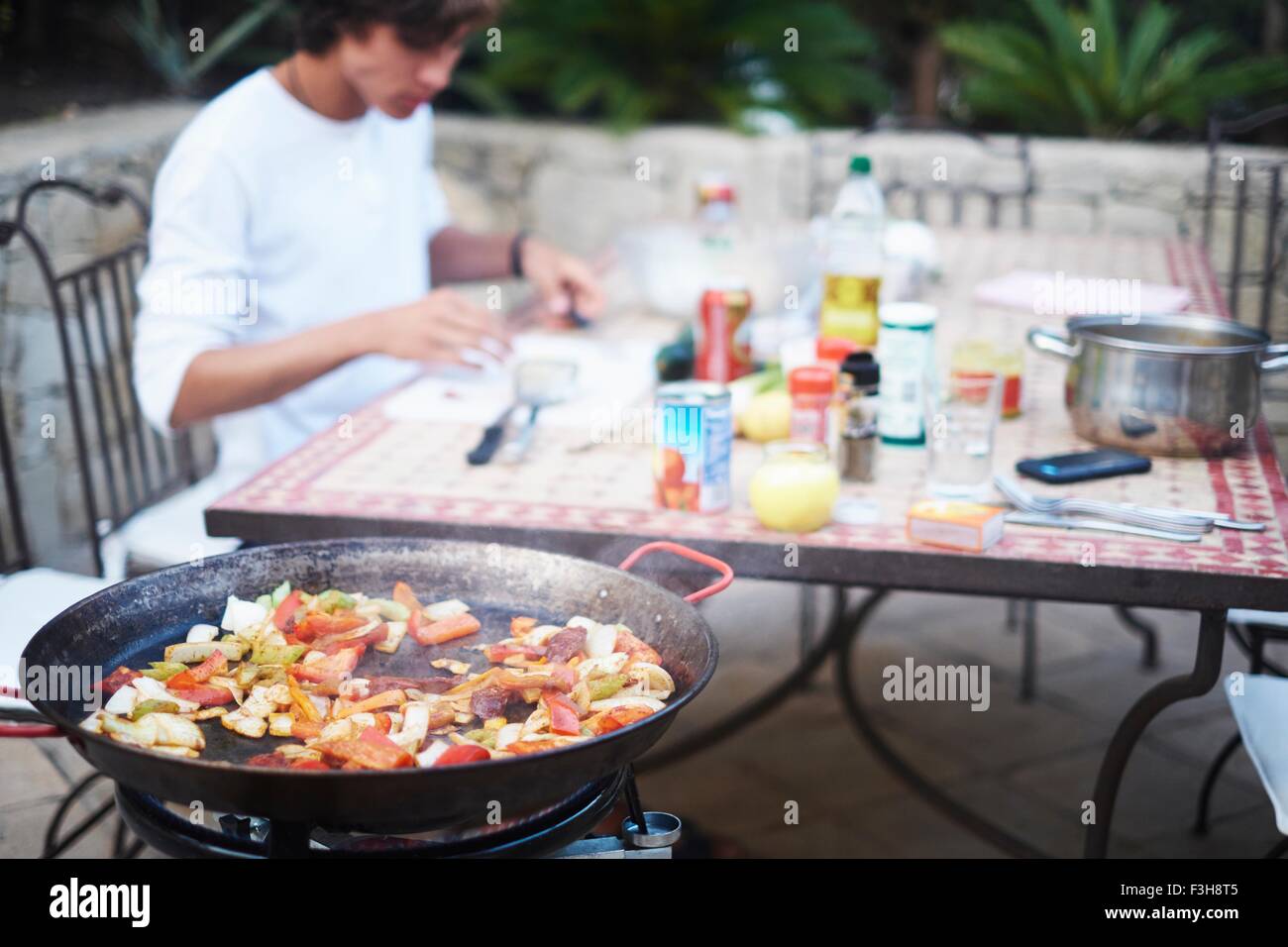 Young man eating stir fried lunch at patio table Stock Photo