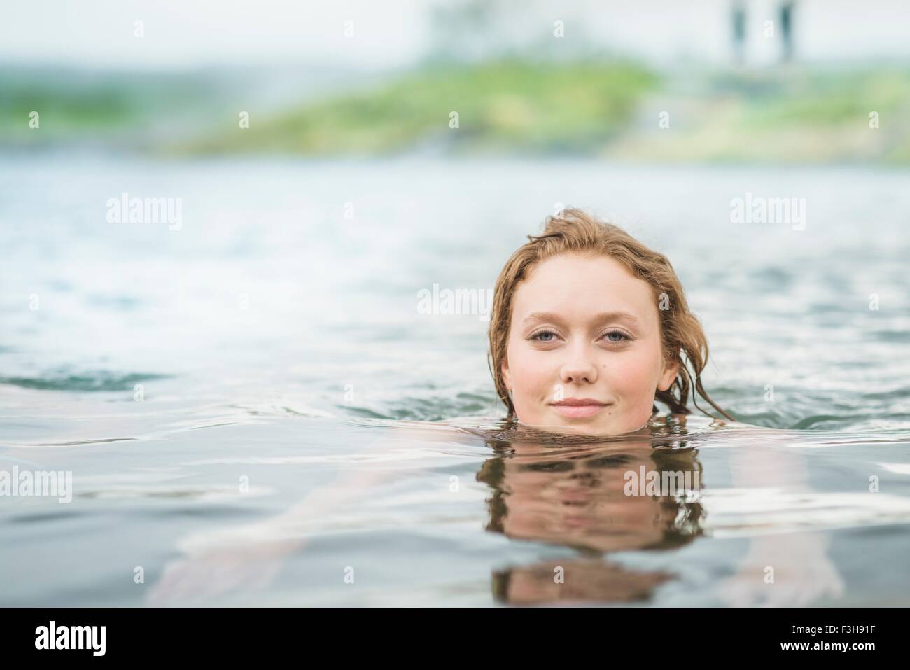Portrait of serene young woman swimming in Secret Lagoon hot spring (Gamla Laugin), Fludir, Iceland Stock Photo