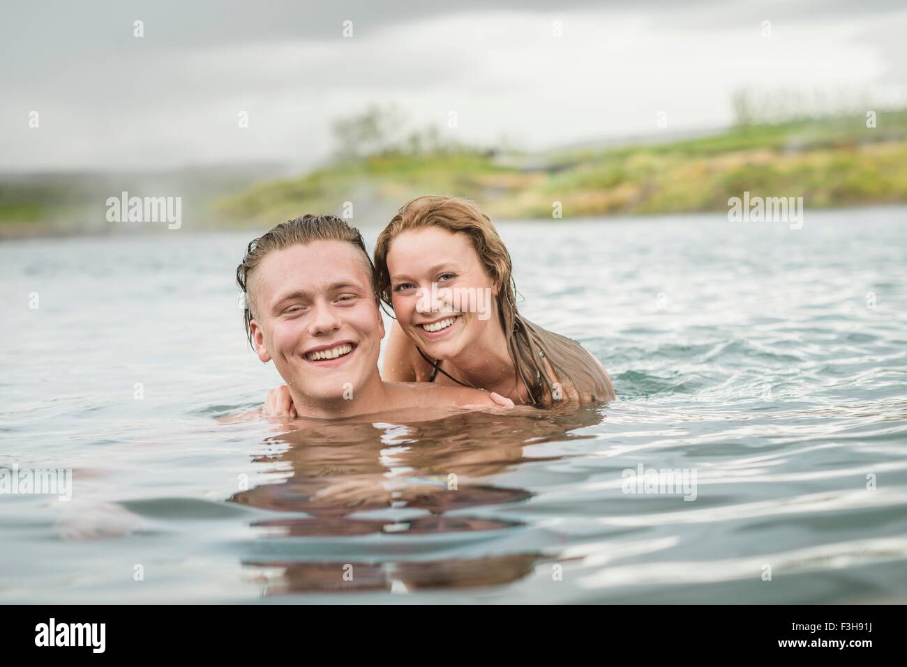 Portrait of smiling young couple relaxing in Secret Lagoon hot spring (Gamla Laugin), Fludir, Iceland Stock Photo