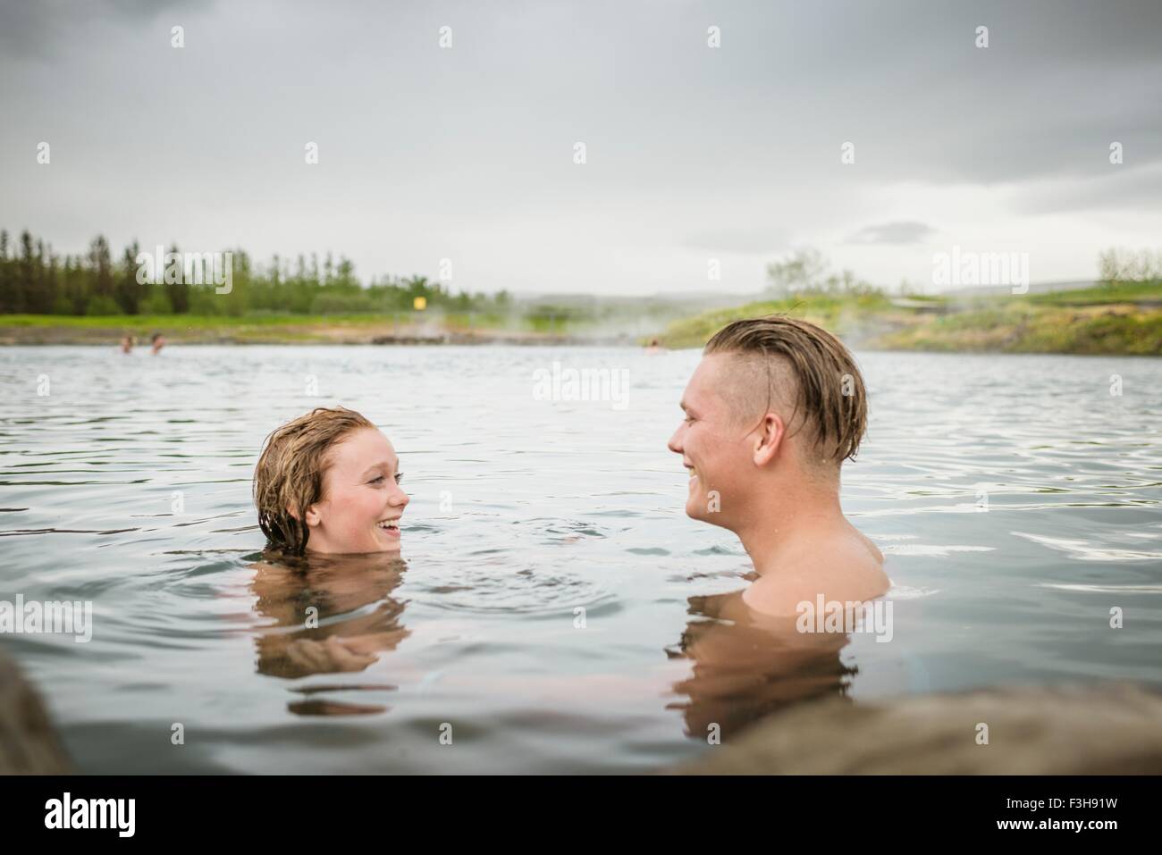 Smiling young couple relaxing in Secret Lagoon hot spring (Gamla Laugin), Fludir, Iceland Stock Photo